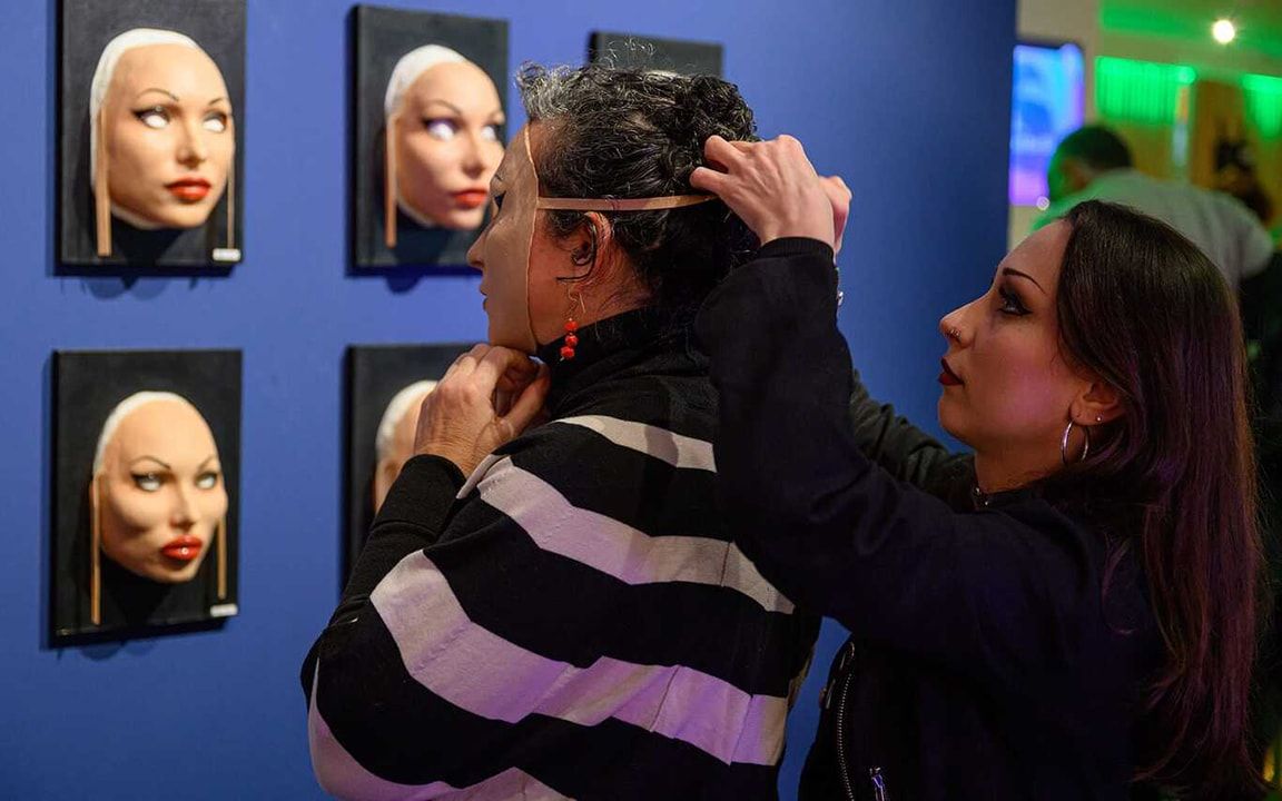 Kunstenaar Laura a Dima maakt een masker vast op het hoofd van een bezoeker